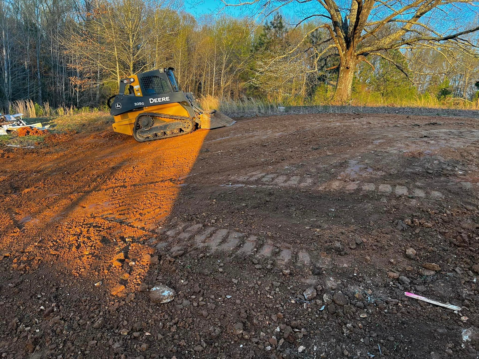 A bulldozer is moving dirt in a field with trees in the background.