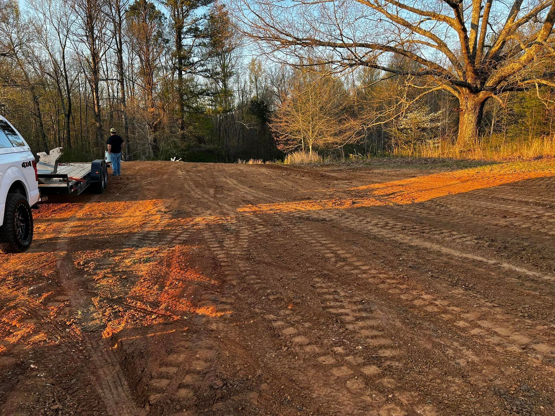 A white truck is parked on the side of a dirt road.