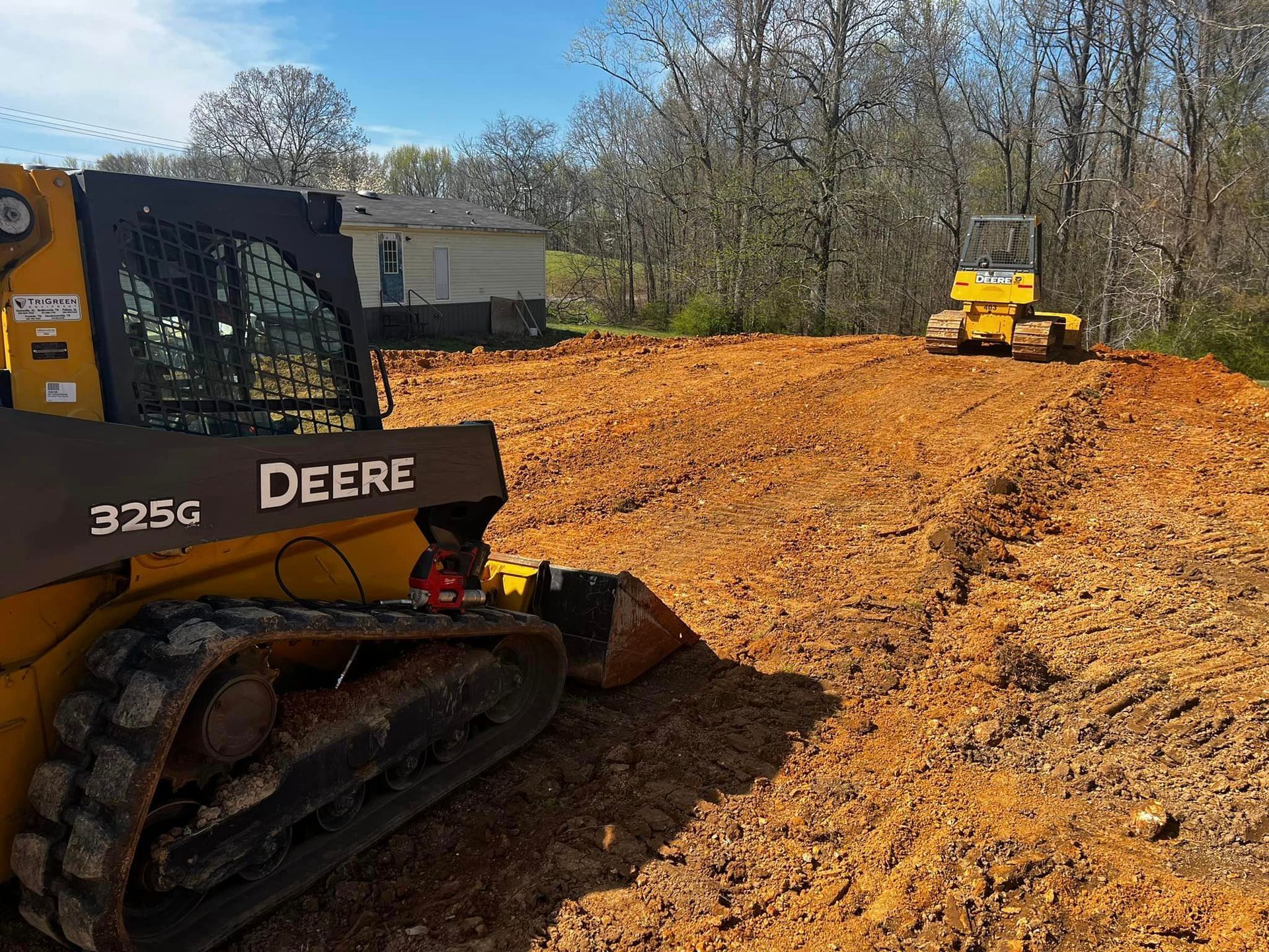A yellow deere bulldozer is sitting on top of a dirt field.