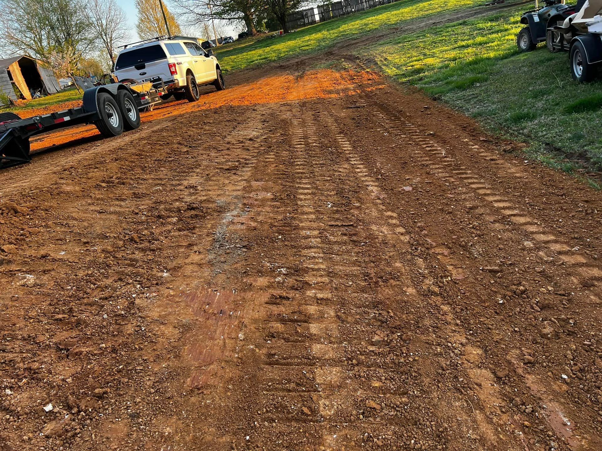 A truck and trailer are parked on a dirt road.