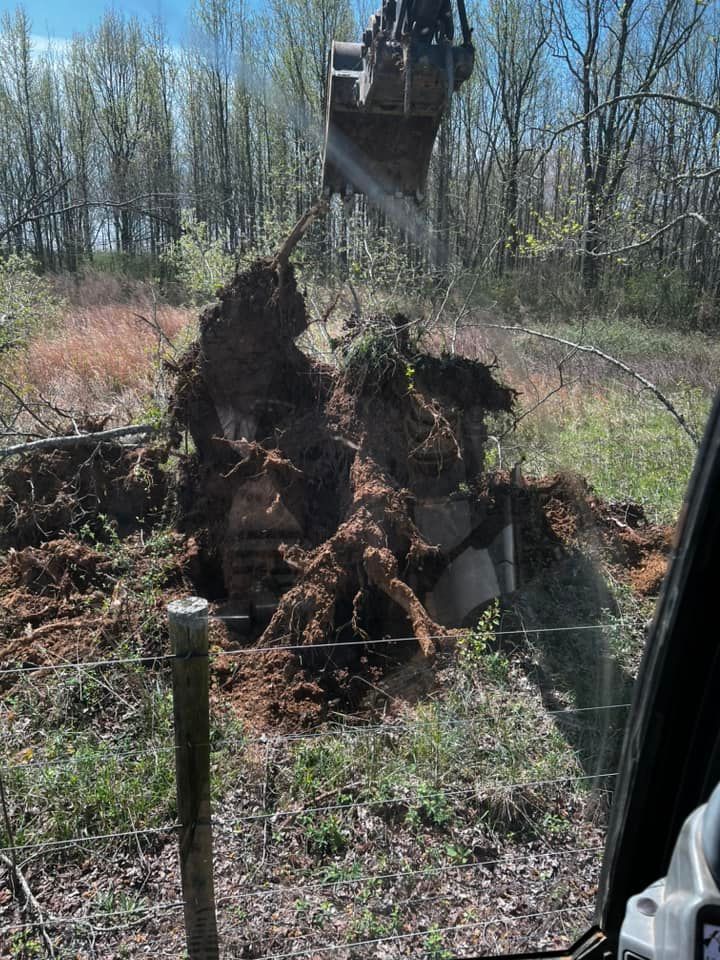 A large tree stump is being removed by a bulldozer in a field.