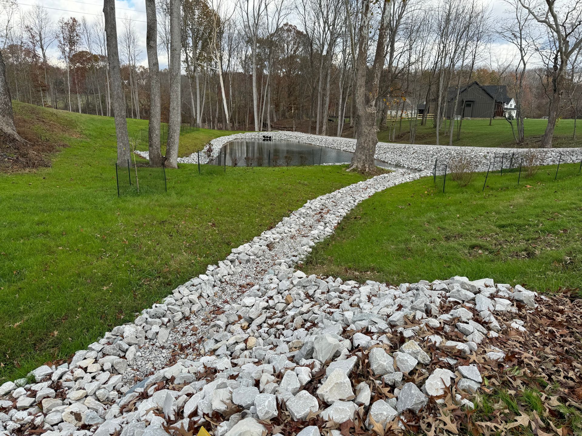 A path leading to a pond in the middle of a grassy field.
