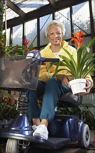 Senior riding on a scooter with a pot of flower
