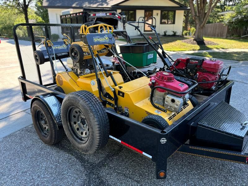 A trailer with a lawn mower on it is parked in front of a house.