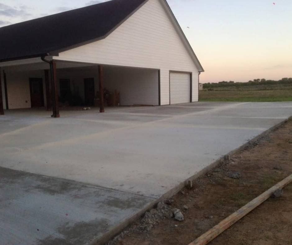 A white house with a concrete driveway in front of it