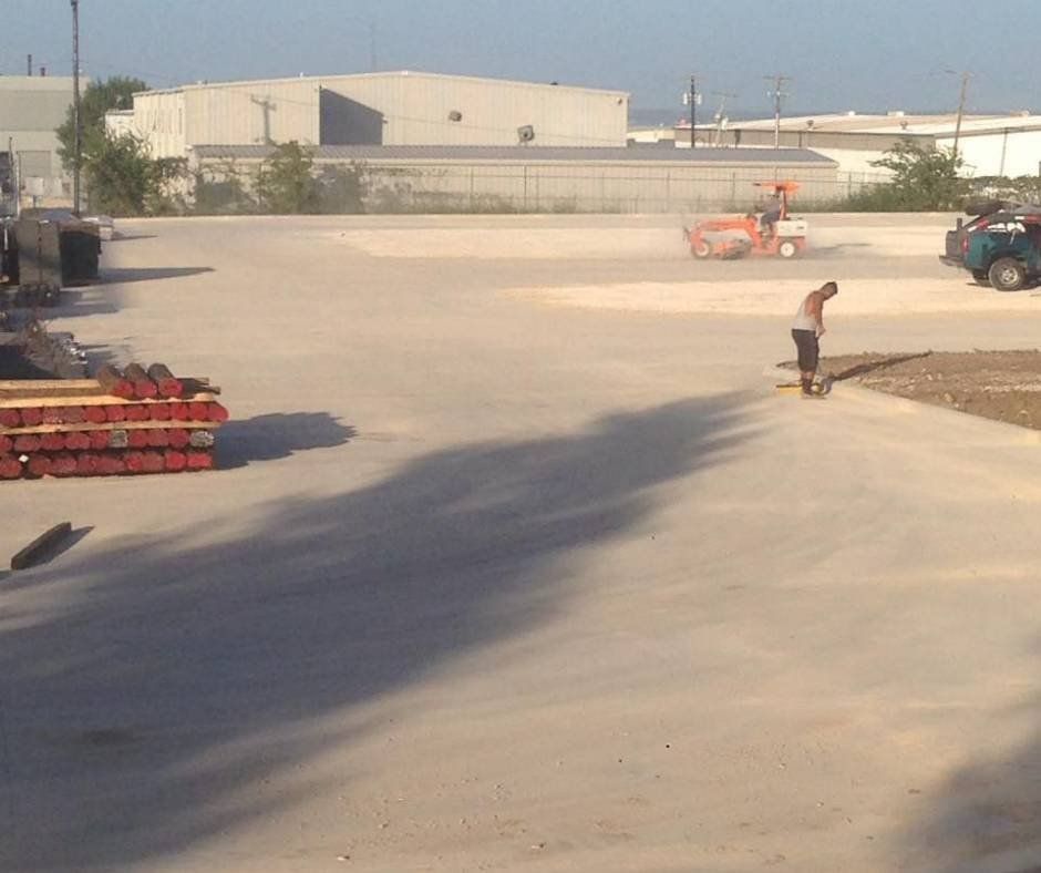 A man is standing in a parking lot next to a stack of pipes