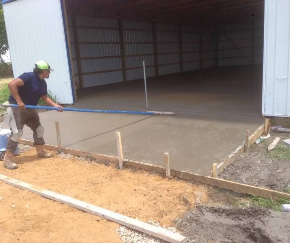 A man is working on a concrete driveway in front of a garage.