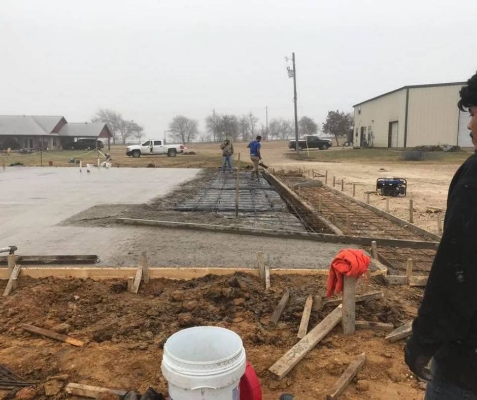 A man is standing in a construction site with a bucket in the foreground.