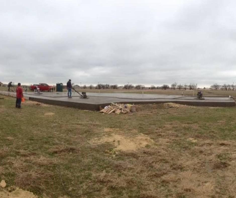 A group of people are working on a concrete floor in a field.