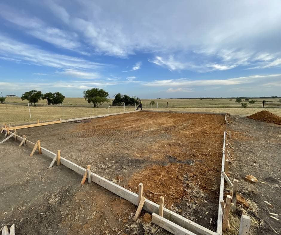 A large dirt field with a fence around it and a blue sky in the background.