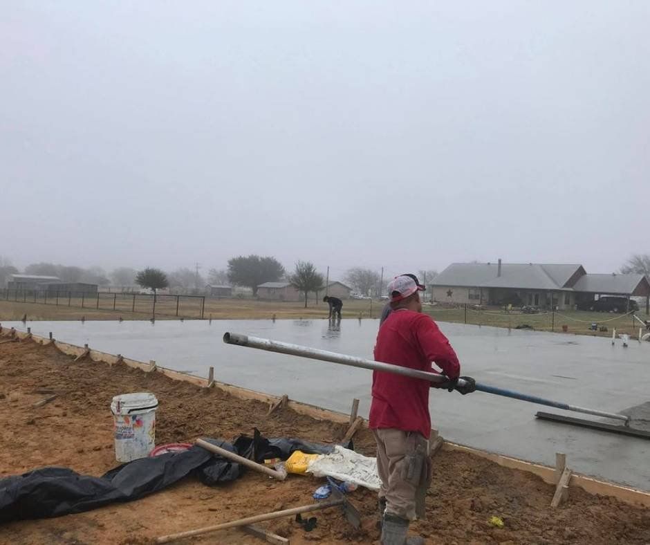 A man in a red jacket is standing on a concrete surface holding a long pole.