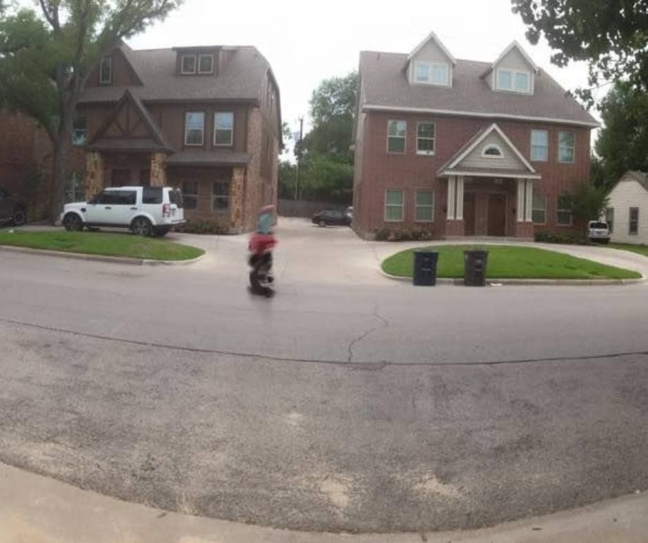 A white suv is parked in front of a brick house