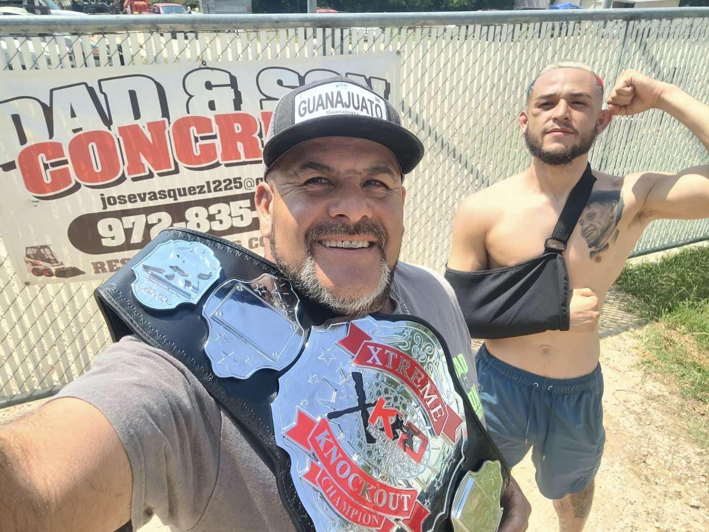 Two men are posing for a picture in front of a sign that says dad & concre