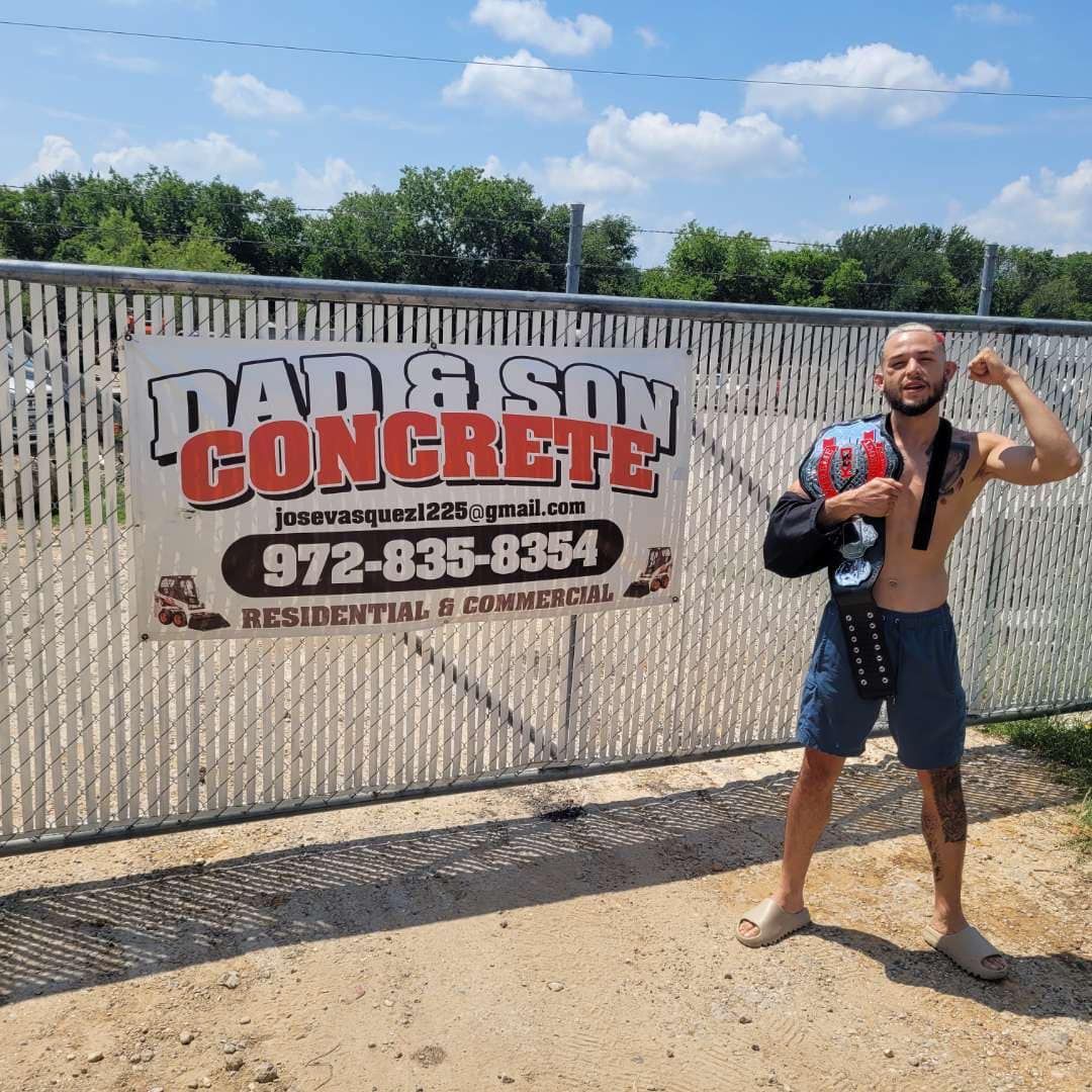 A shirtless man is standing in front of a sign for dad & son concrete