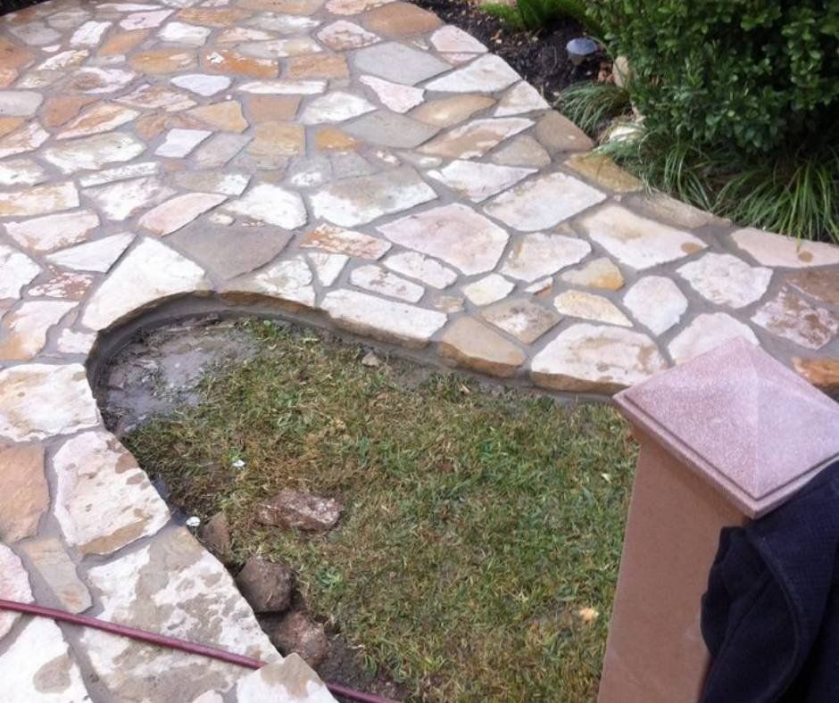 A stone walkway with a hose in the grass