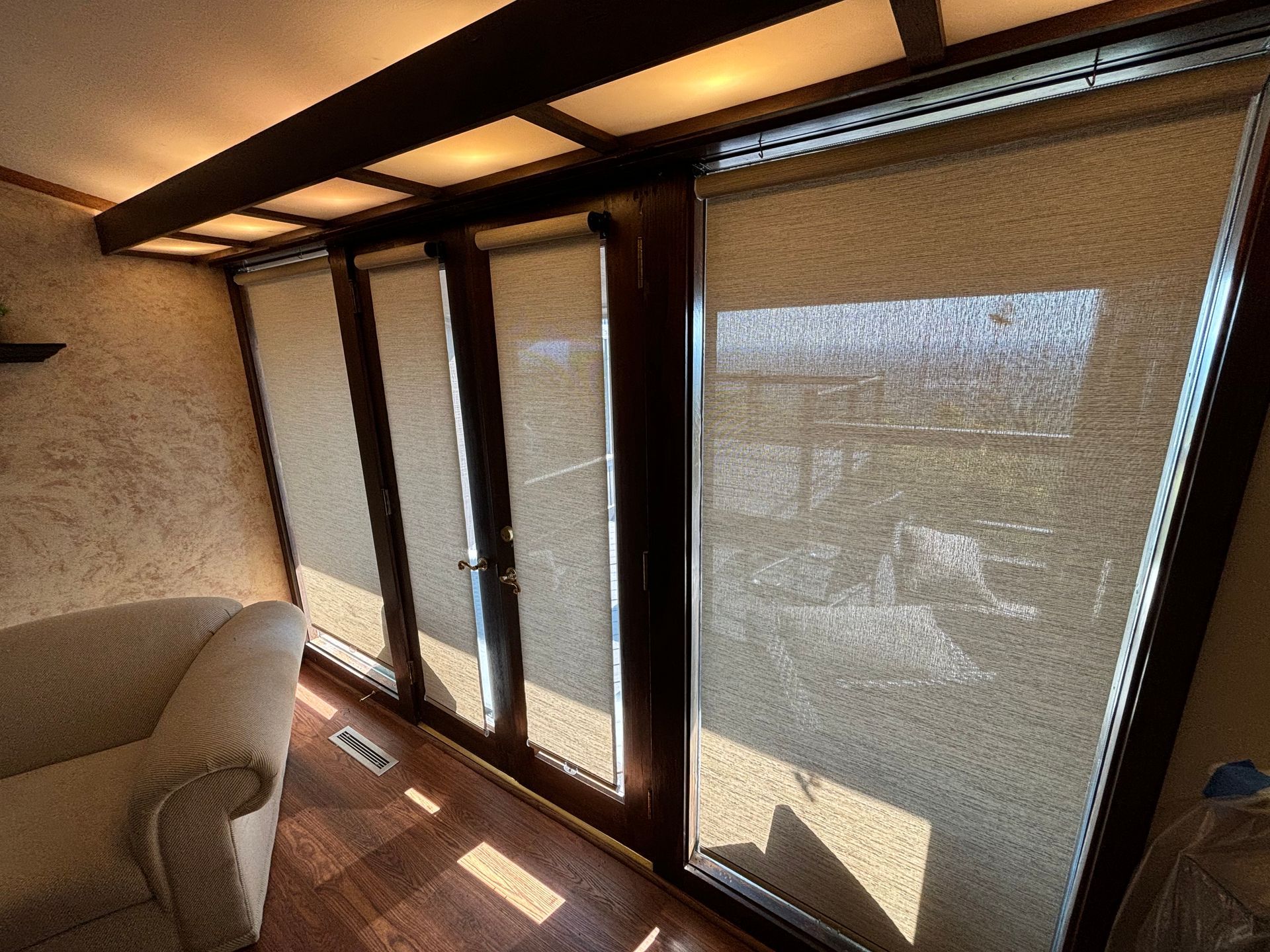 A living room with a chair and sliding glass doors with blinds on them.