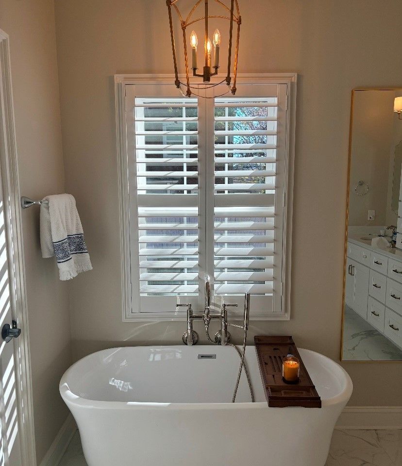 A bathroom with a bathtub and a window with shutters