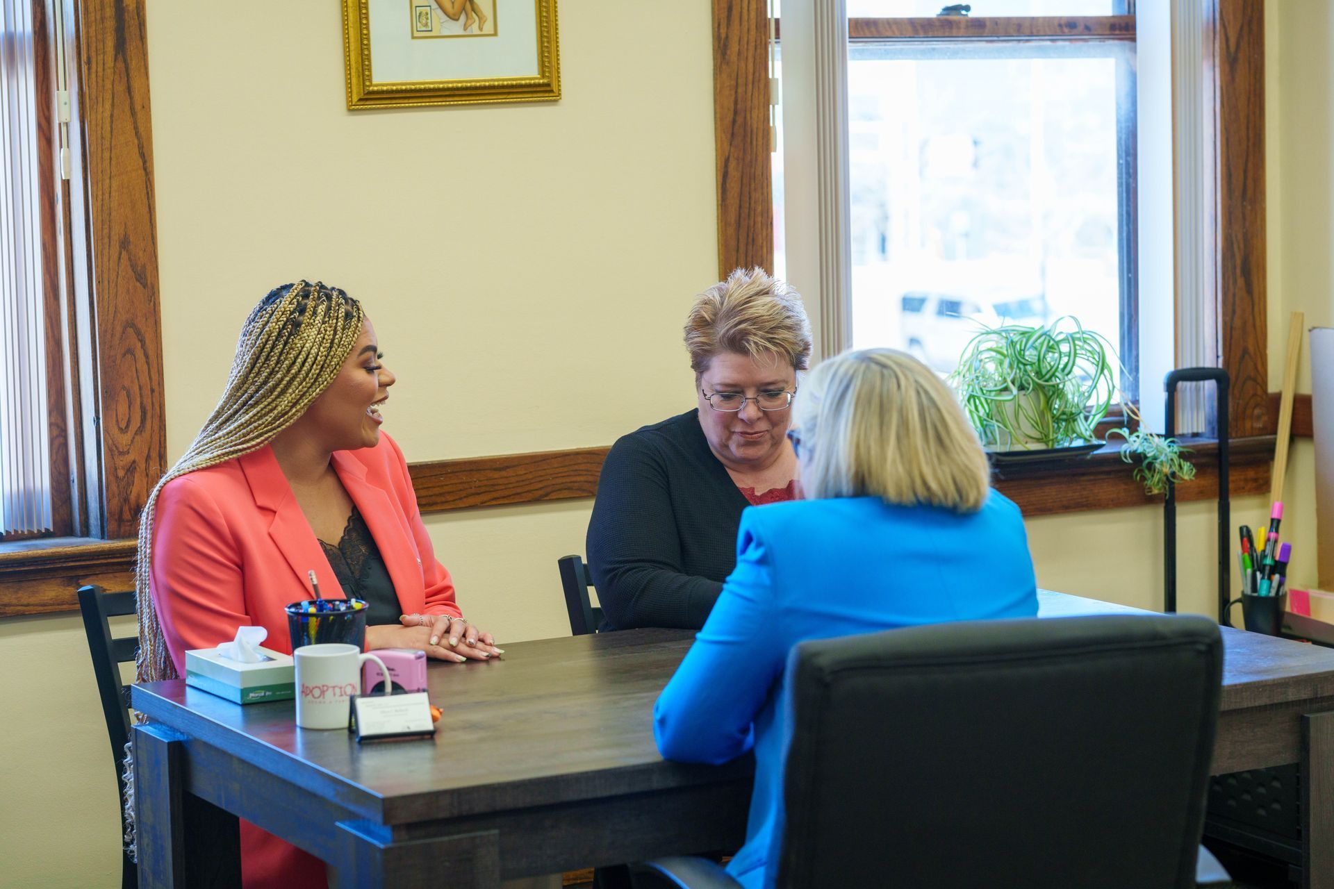 Three women are sitting at a table talking to each other.