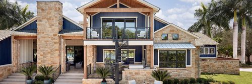 Modern two-story stone and wood house with a central balcony and large windows