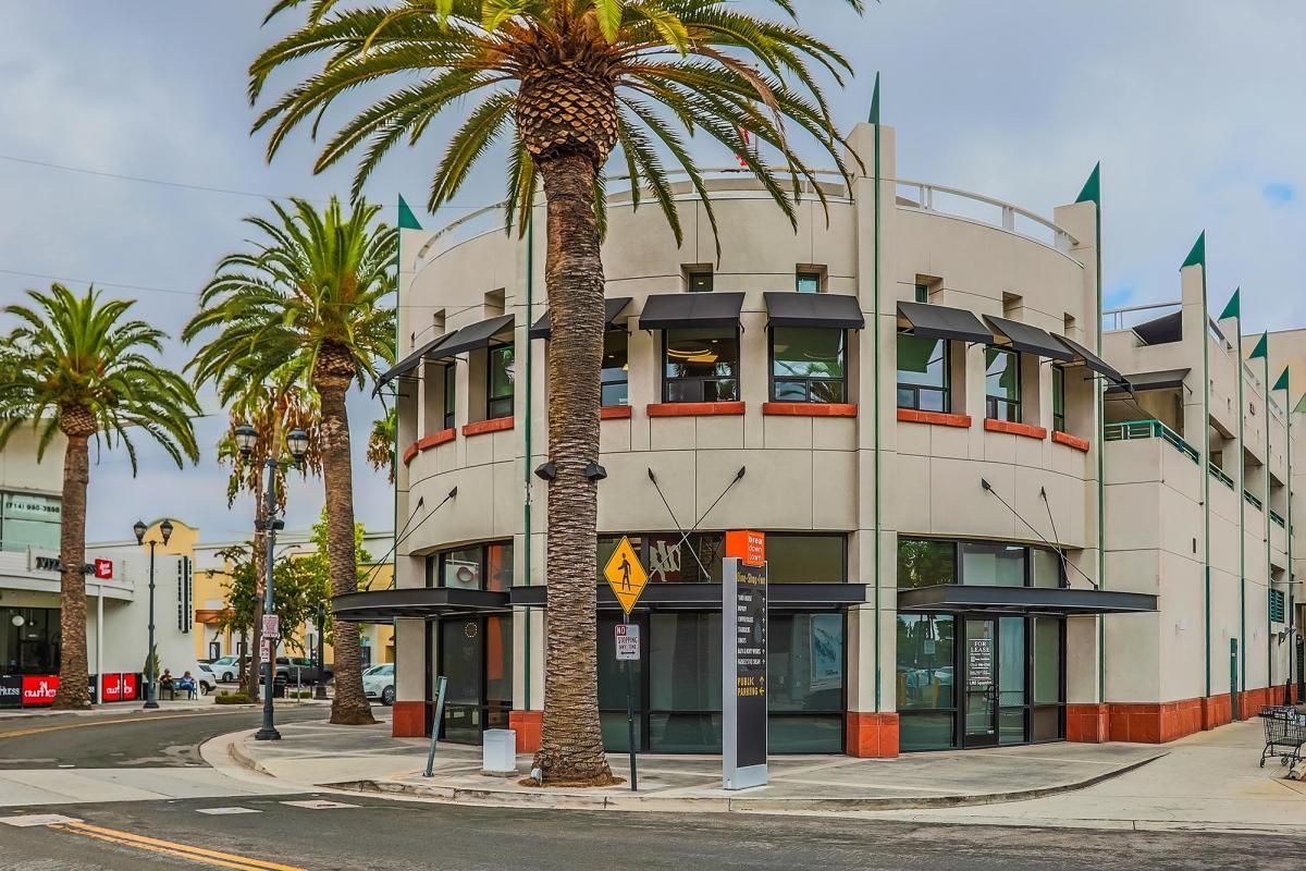 Corner building with palm trees and green-trimmed windows on a sunny street corner
