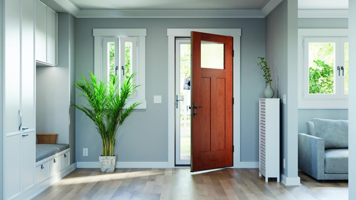 Bright modern entryway with an open wooden door, potted plant, and gray couch in the background
