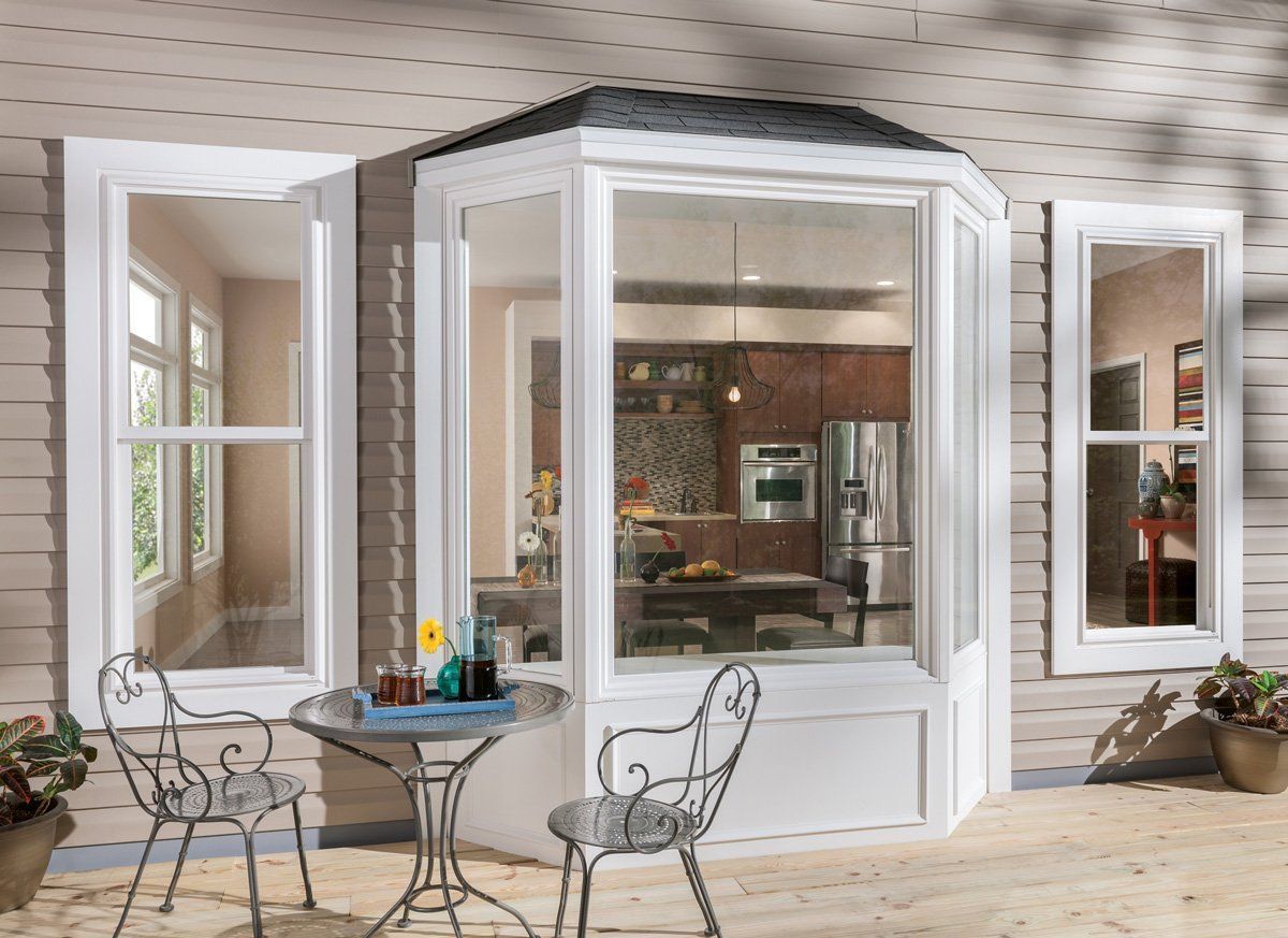 Outdoor patio with white patio doors and a small table and chairs outside a kitchen window