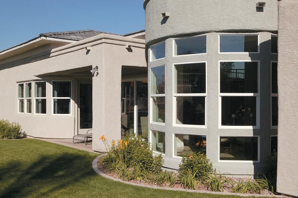 Exterior of a beige building with white-trimmed windows and a curved glass corner