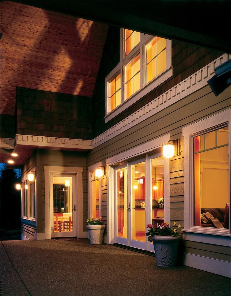 Warmly lit storefront windows and doors along a covered building walkway at dusk.