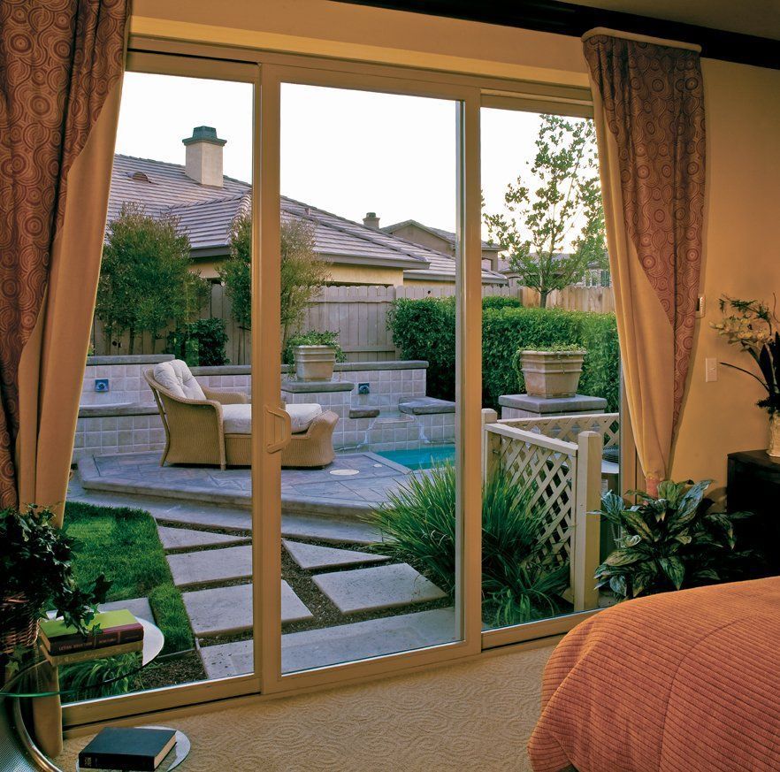 Bedroom sliding door opens to a backyard patio with pool, lounge chairs, and potted plants at dusk