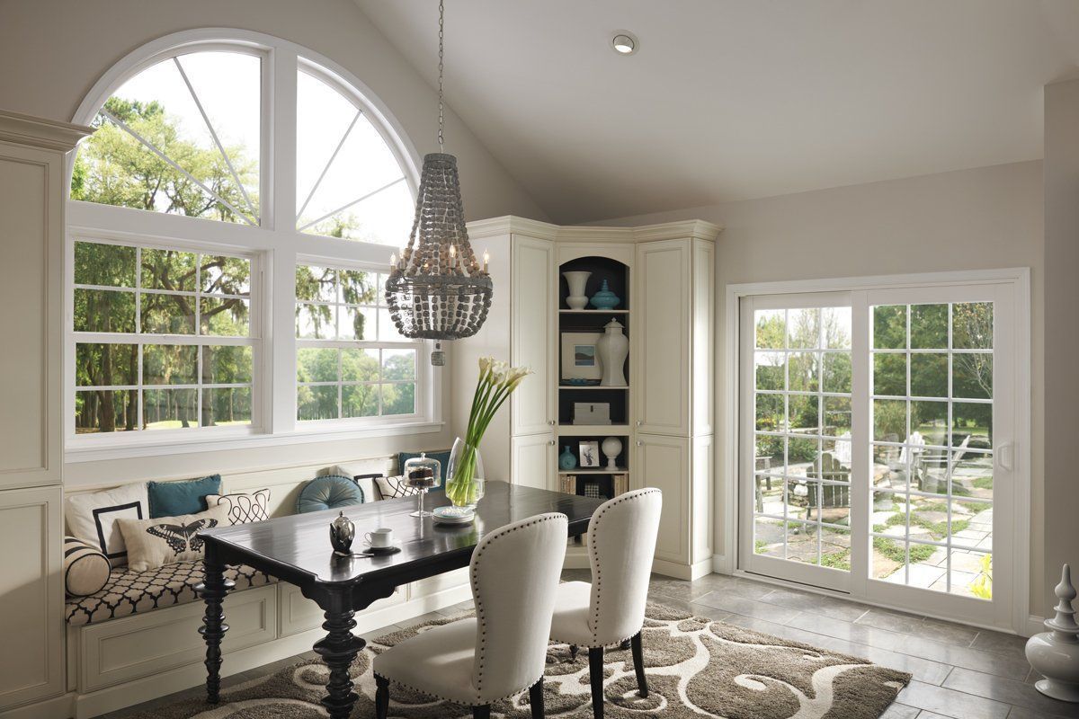 Bright dining room with white chairs, dark table, large windows, and a hanging pendant light