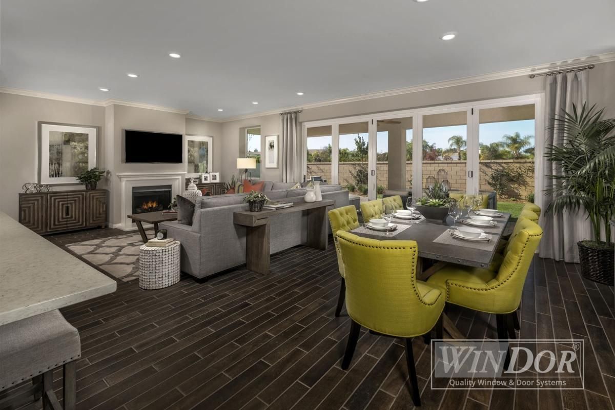 Modern open-concept living and dining room with gray sofa, lime chairs, and large windows overlooking greenery