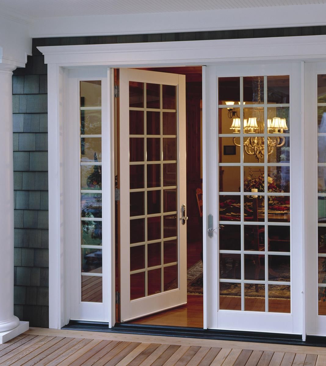 Open white French doors leading into a warmly lit home interior