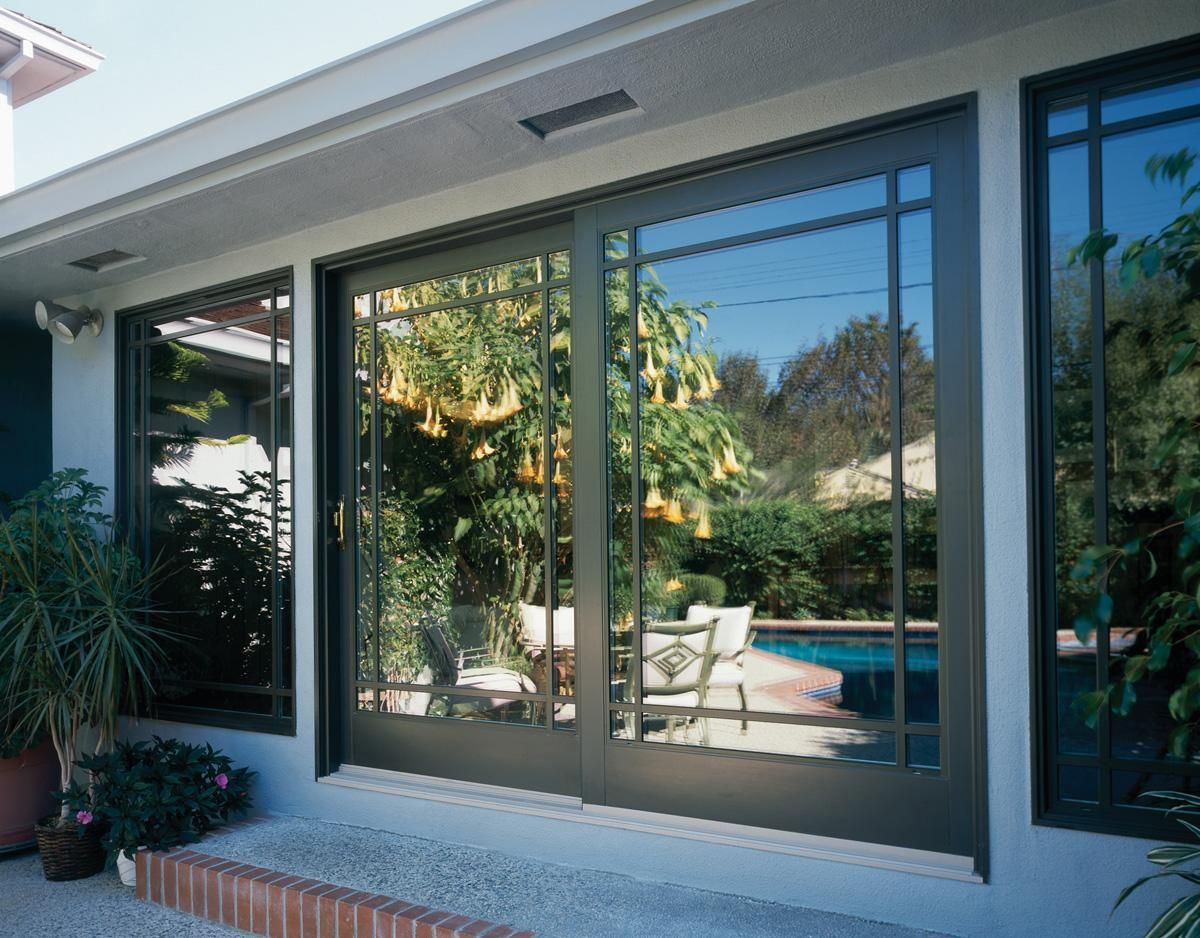 Patio window overlooking a sunny backyard with a swimming pool and trees