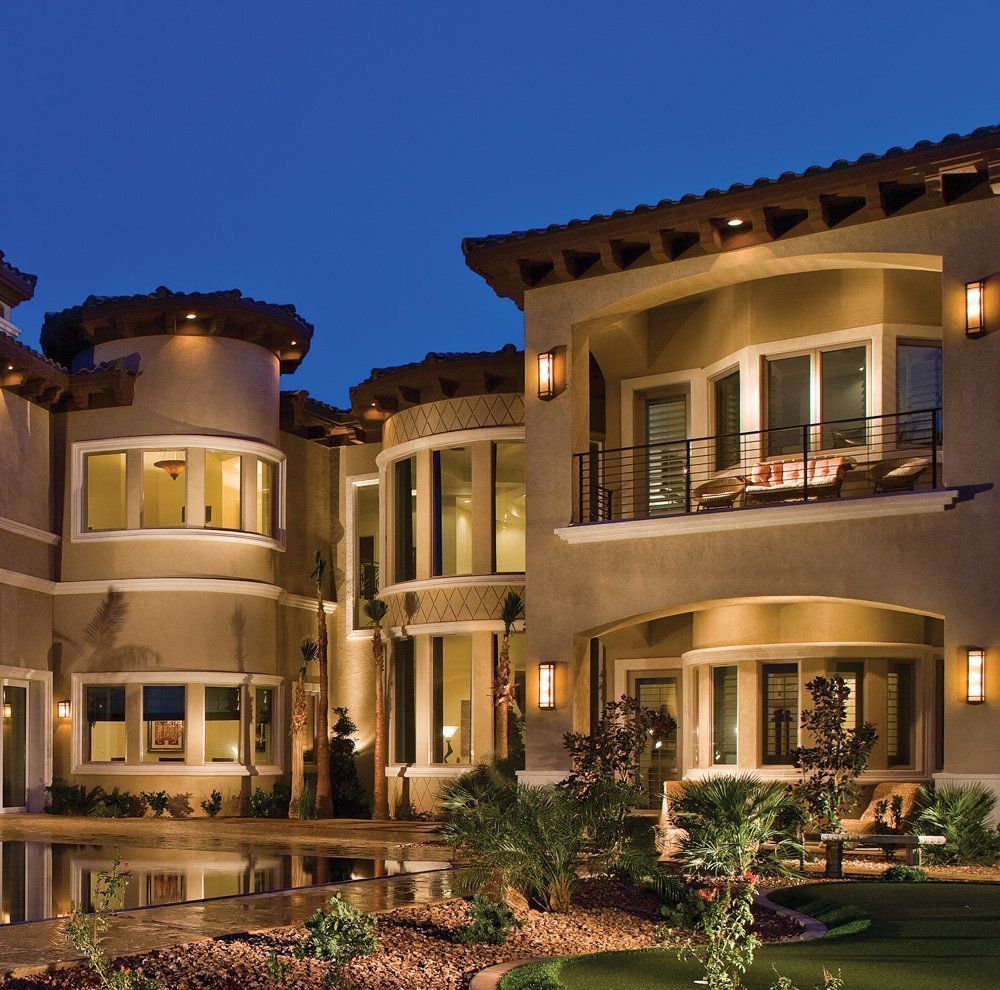 Luxury stucco townhomes lit at dusk with balconies and landscaped courtyard