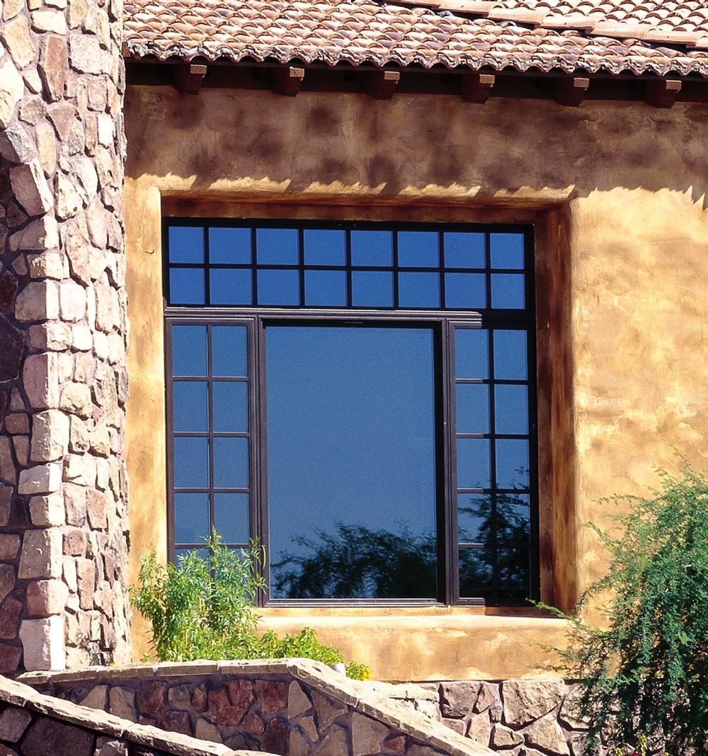 Window with dark blue panes set in a rustic stucco wall and stone trim