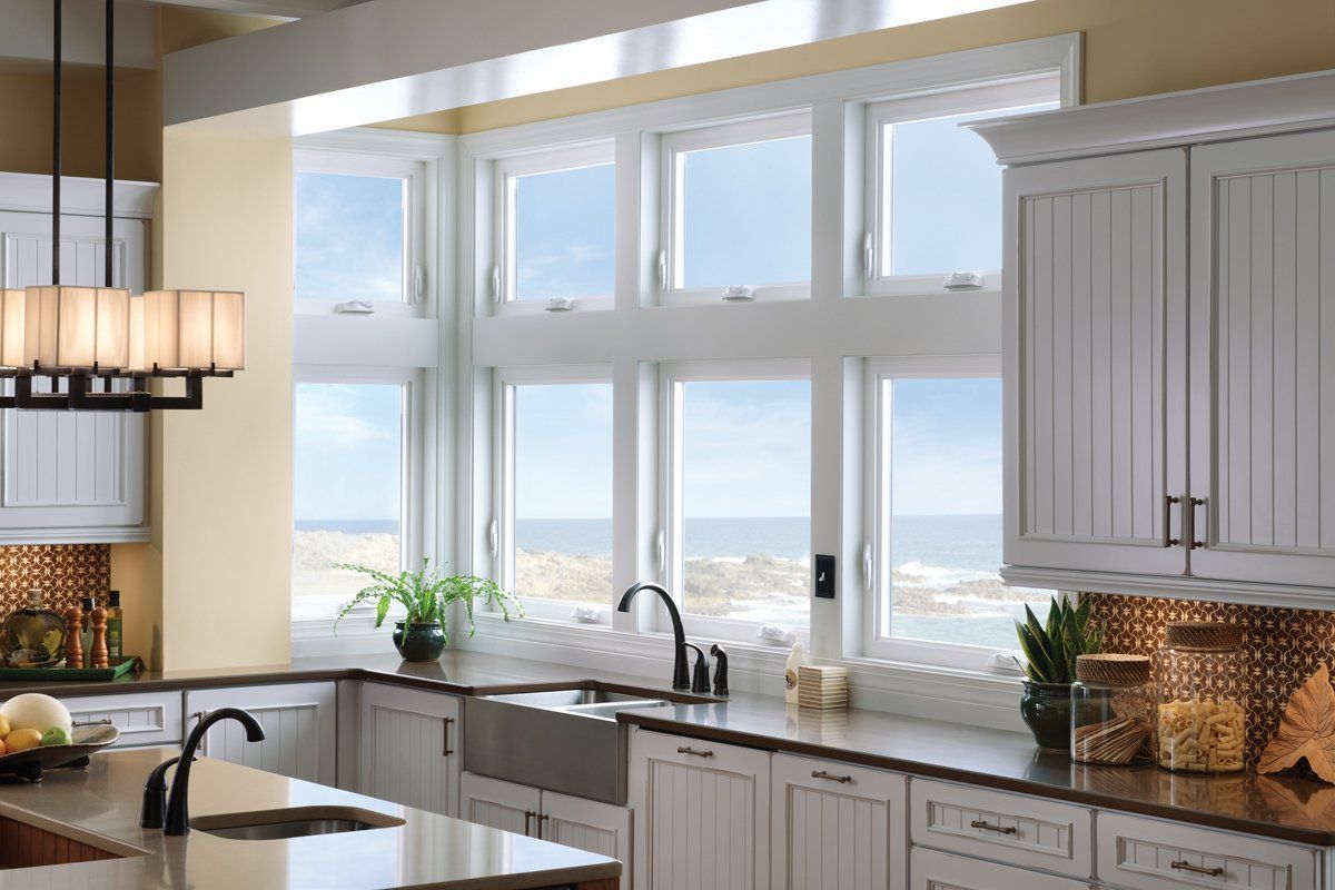 Bright kitchen with large window over sink, white cabinets, and a view of the water outside.
