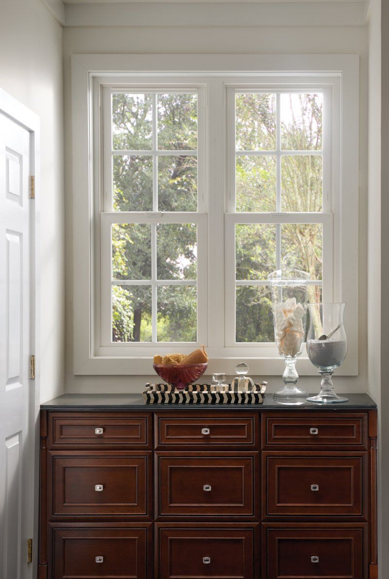 Dresser beneath a bright window with decorative items and a chess set on top