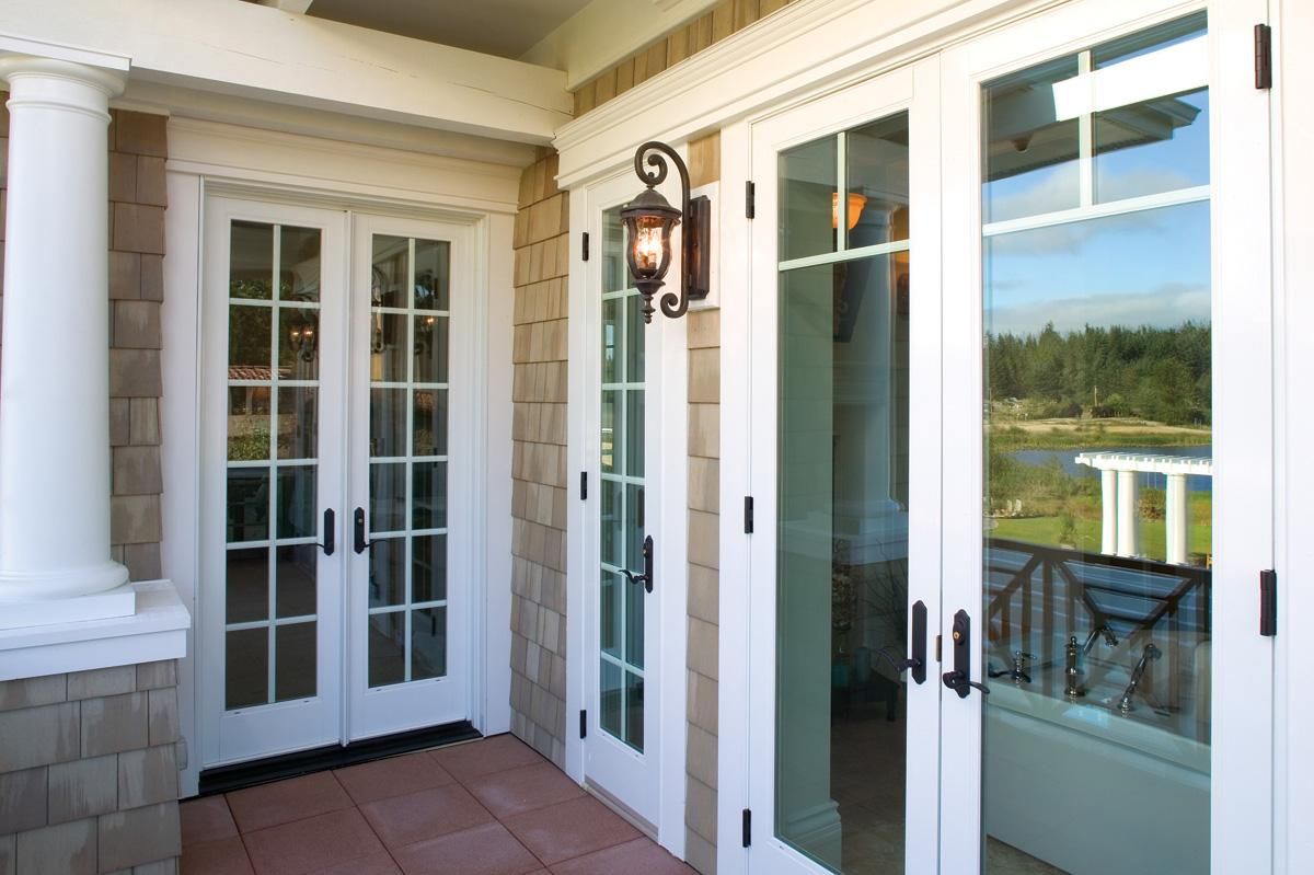 Front porch with white French doors, glass windows, and a hanging lantern beside a lake view