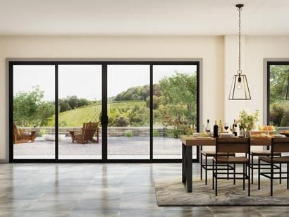 Modern dining room with large sliding glass doors opening to a patio and green landscape