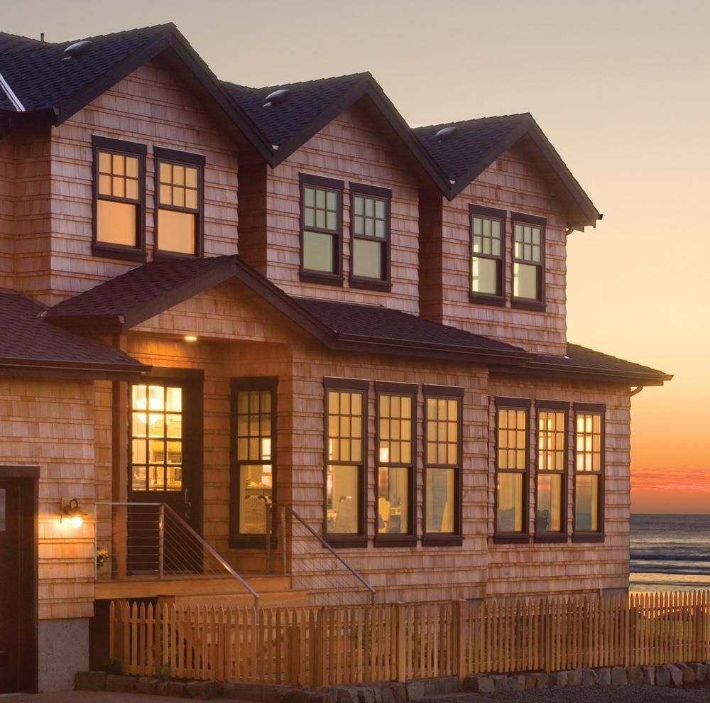 Two-story beach house at sunset with warm lights and ocean view