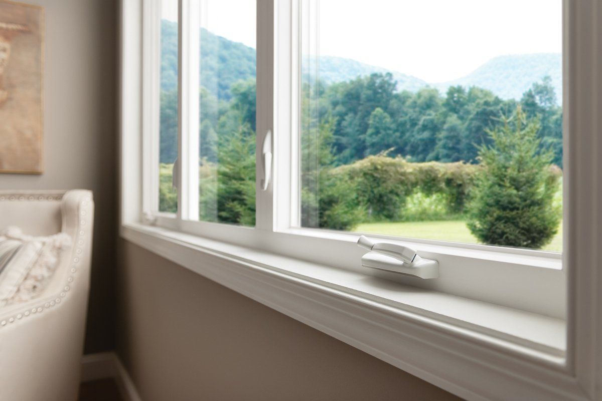 Open window overlooking green trees and hills, with white windowsill and beige wall interior