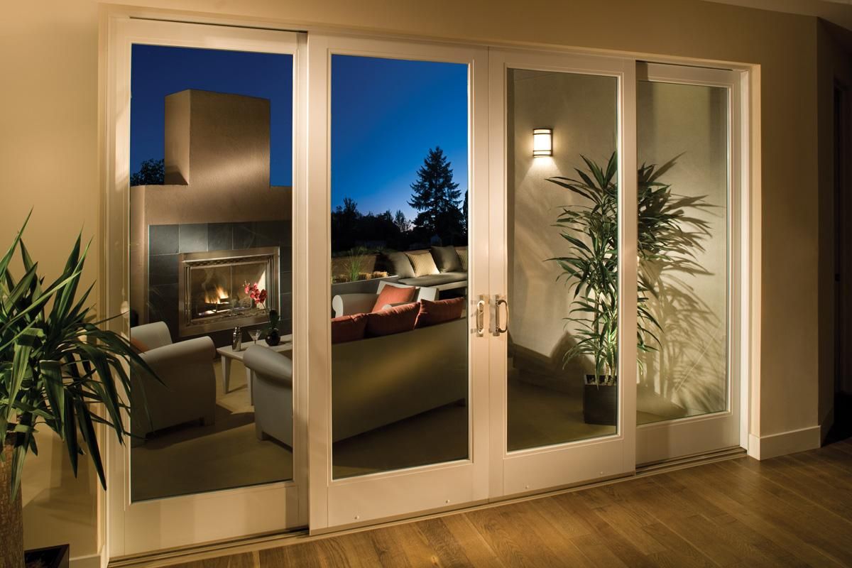 Modern living room with glass doors, warm lighting, and a view of the outdoors at dusk