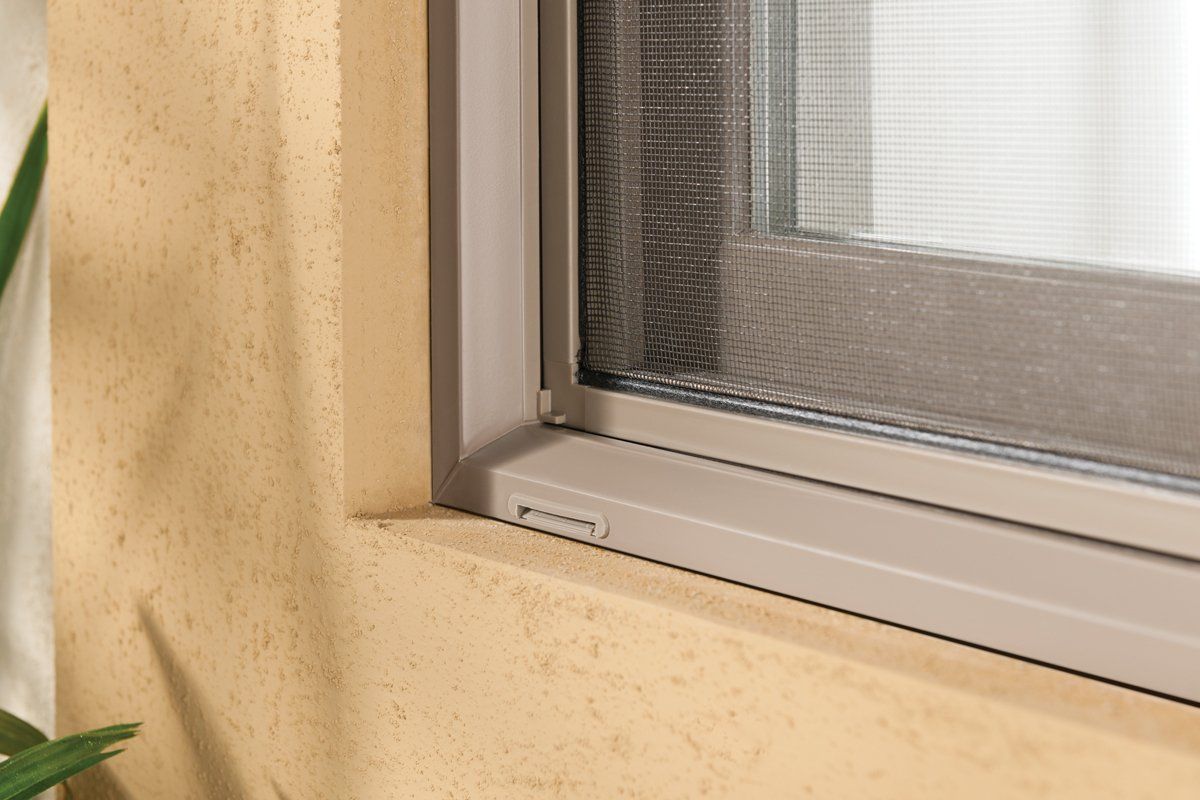 Close-up of a window frame with a screen and beige wall trim
