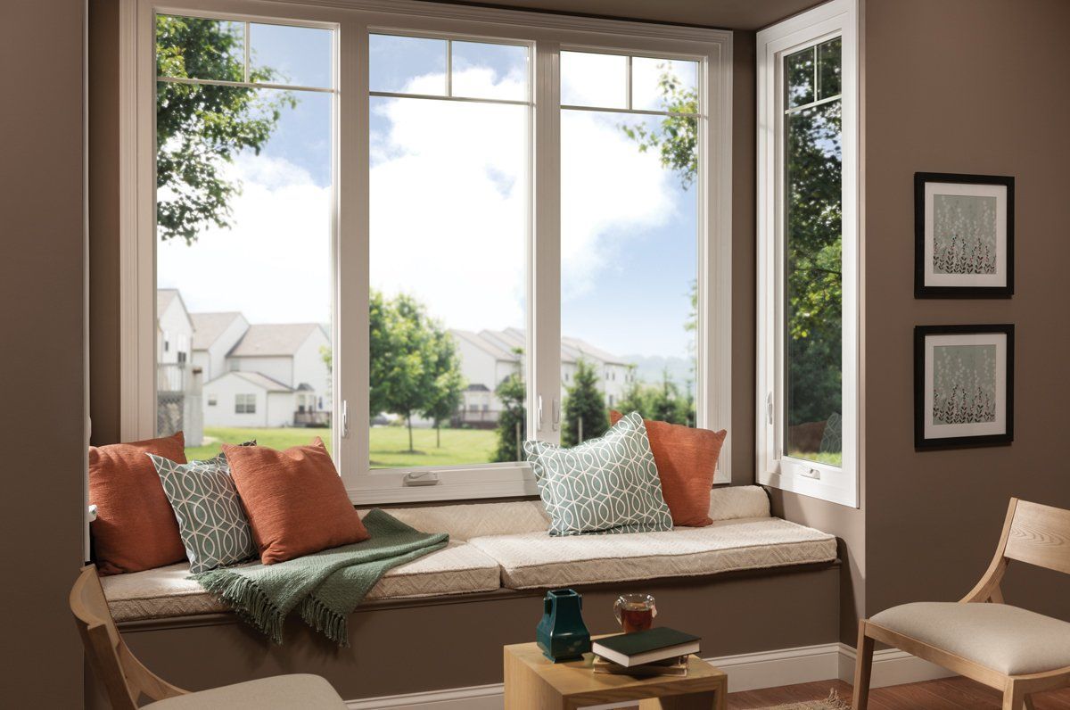 Cozy bay-window reading nook with orange and green pillows, overlooking a bright suburban yard.