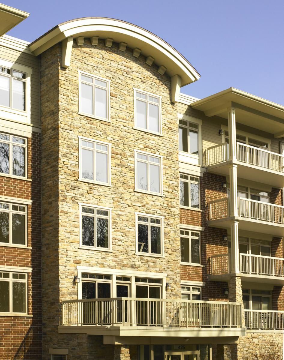 Modern apartment building with brick facade, balconies, and large windows under a clear sky