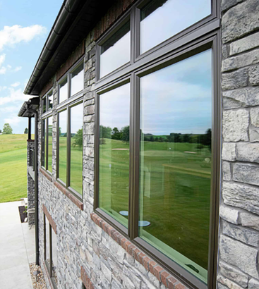Stone building exterior with large windows overlooking a green golf course