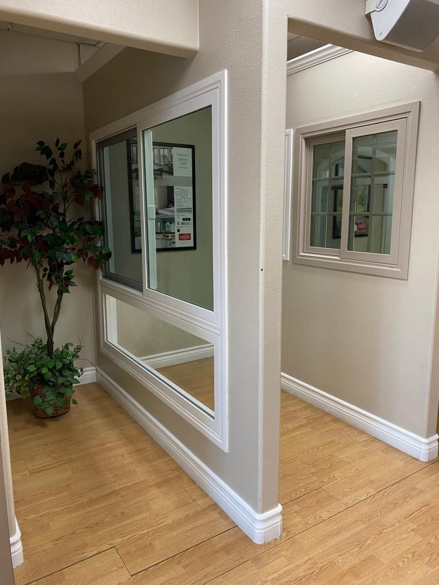 Indoor hallway with a large wall mirror, white trim, wood floor, and a small window opening.