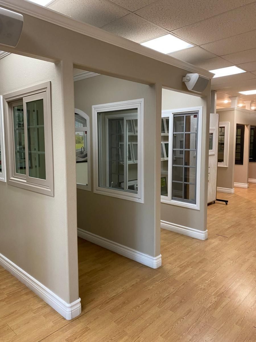 Interior hallway with white-framed display windows and wood flooring under recessed lights