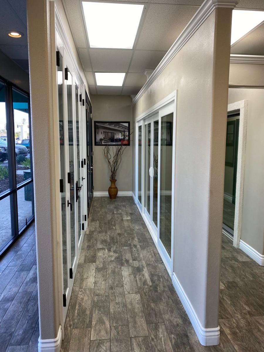 Modern office hallway with glass doors, gray flooring, and ceiling lights