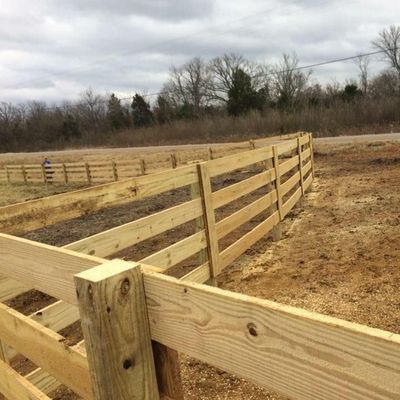 Wooden fence in a field under a cloudy sky.
